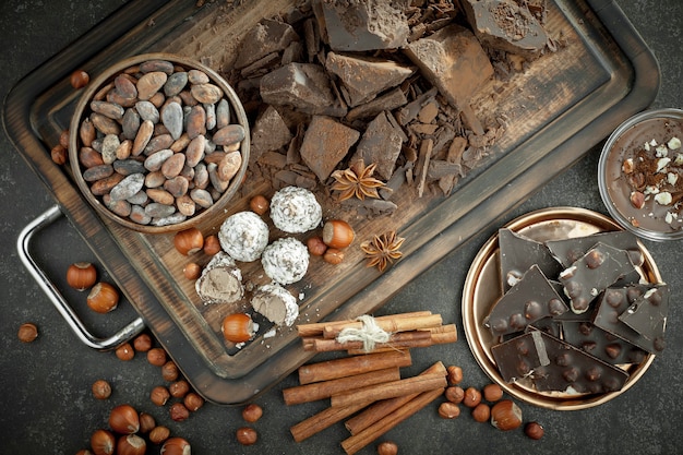 Donkere chocolade in een compositie met cacaobonen en noten, op een oude achtergrond.