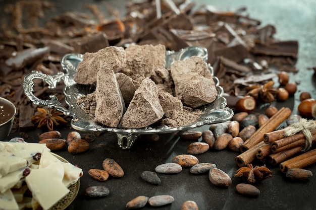 Donkere chocolade in een compositie met cacaobonen en noten, op een oude achtergrond.