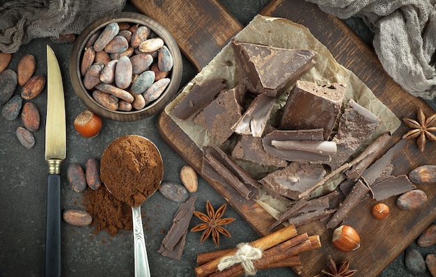 Donkere chocolade in een compositie met cacaobonen en noten, op een oude achtergrond.