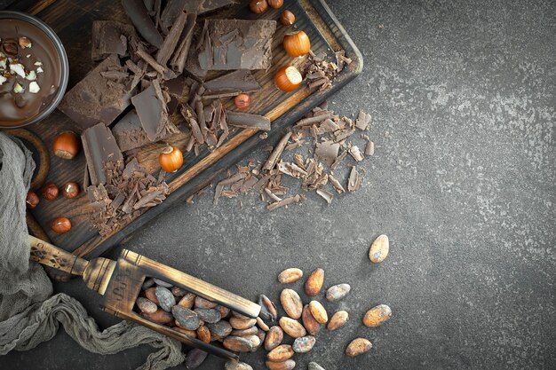 Donkere chocolade in een compositie met cacaobonen en noten, op een oude achtergrond.