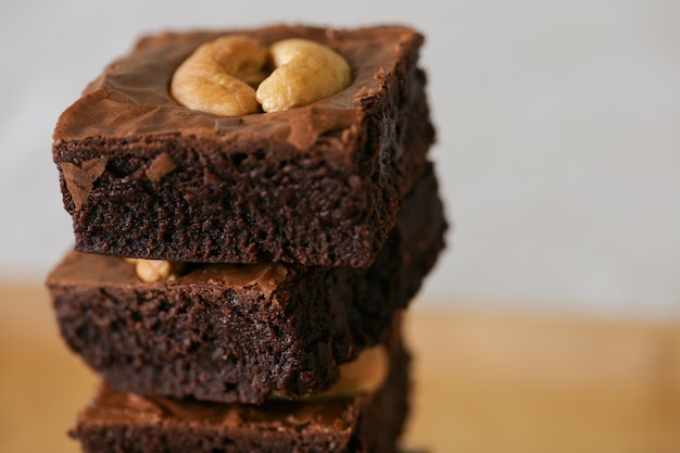 Donkere chocoladezachte toffee brownies die cashewnotenstapel op houten plaat bedekken met exemplaarruimte. heerlijke smaak bitter zoet, taai en fudgy. brownie is een soort chocoladetaart. zelfgemaakt bakkerijconcept