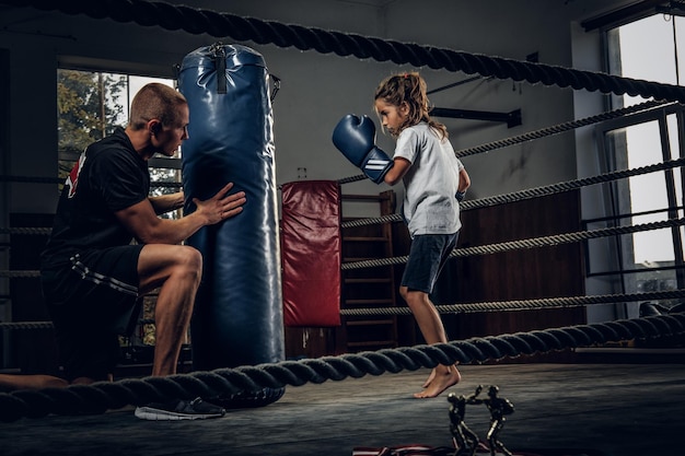 Donkere fotoshoot van kinderen die trainen met een grote bokszak in de boksstudio.