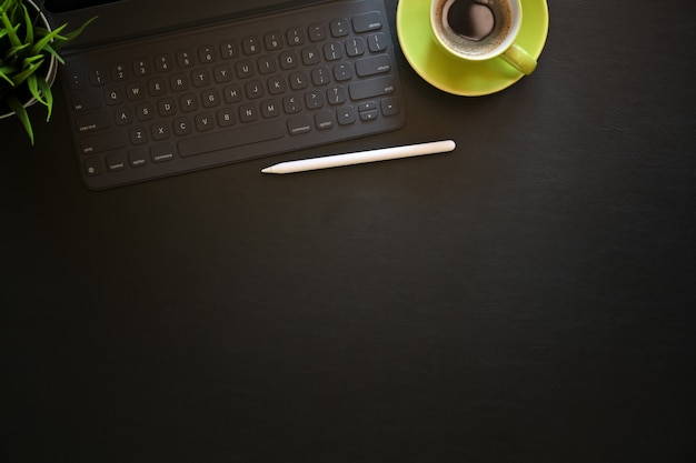 Donkere lederen bureau tafel met koffie, computer en kantoorbenodigdheden.