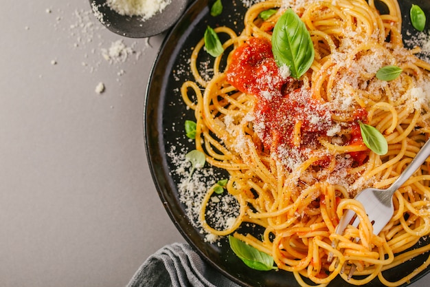 Donkere plaat met Italiaanse spaghetti op grijs