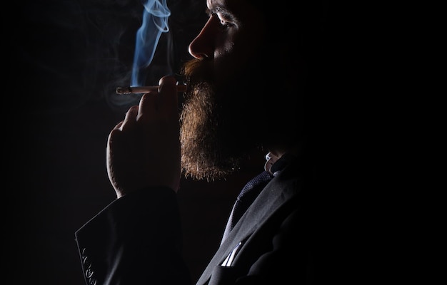 Donkere schaduw op gezicht jonge man roken op een zwarte achtergrond man roken sigaret