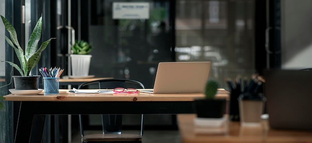 Donkere toon kantoor werkplek. Houten bureau met laptop en documenten, modern interieur van gezellige kast, comfortabele werkruimte, werkplek met computer in huis.