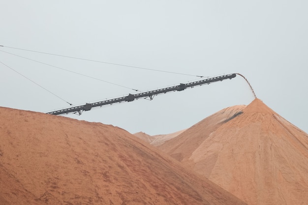 Donkergele bergen zoutstortplaatsen waarop een machine staat voor het winnen van zout