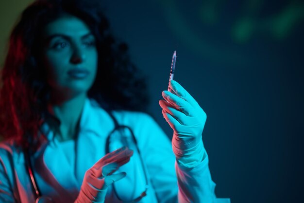 Foto donkerharige dokter met een spuit in de hand