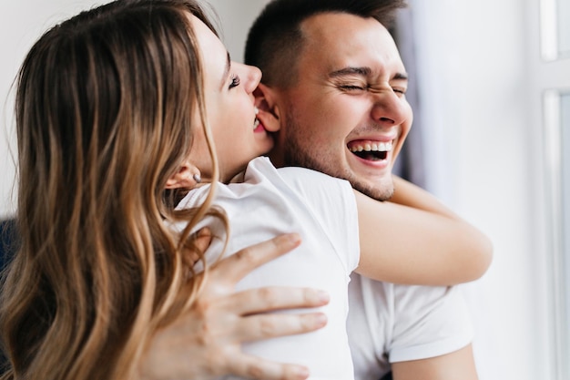 Donkerharige enthousiaste vrouw die met man aan het dollen is. Grappige dame genieten van weekend met vriendje.