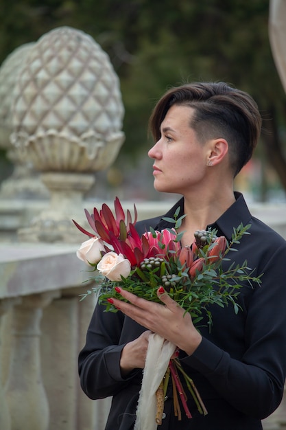 Donkerharige meisje met een boeket bloemen in een voorjaar park, begroeting concept