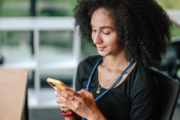 Donkerharige vrouw die een smartphone in de hand houdt en een bericht typt