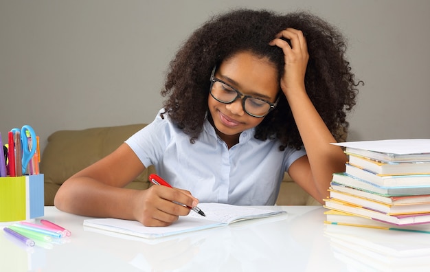 Donkerhuidig schoolmeisje met bril huiswerk