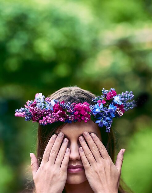 Foto non coprirti gli occhi guarda la bellezza intorno a te inquadratura ritagliata di una bellissima giovane donna che indossa una corona di fiori e si copre gli occhi nella natura