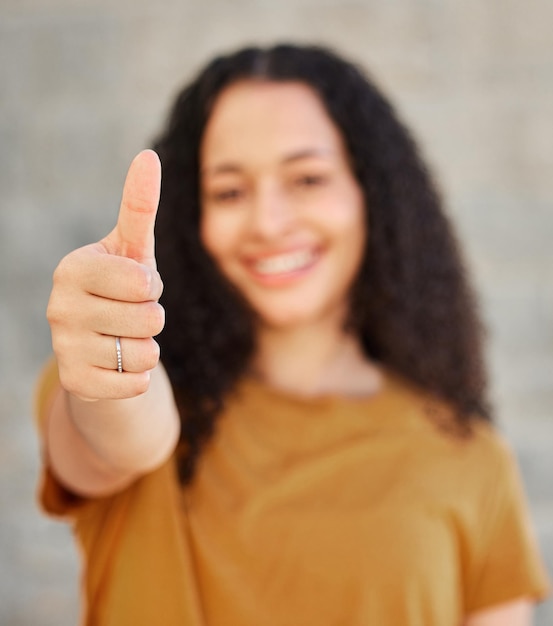 Dont forget to hit like Shot of a young woman showing thumbs up while standing outside