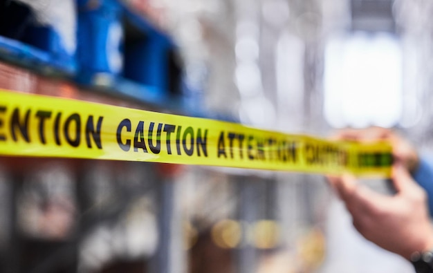 Dont forget to read the sign Shot of a unrecognizable man putting up tape in a warehouse