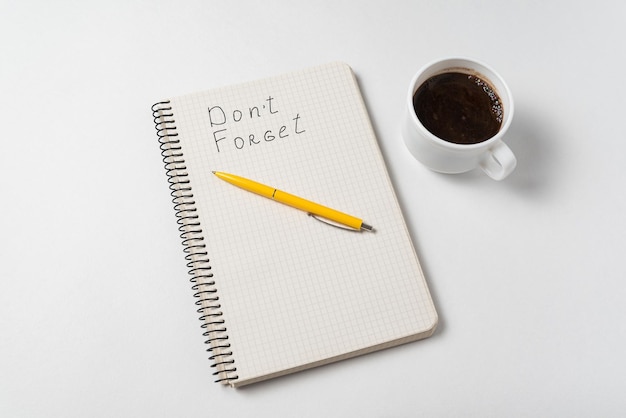 Dont Forget Reminder Notice Notepad pen and cup of coffee on white background