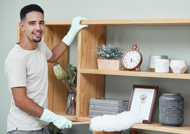 Photo dont give dust the chance to make itself at home shot of a young man dusting a shelf at home