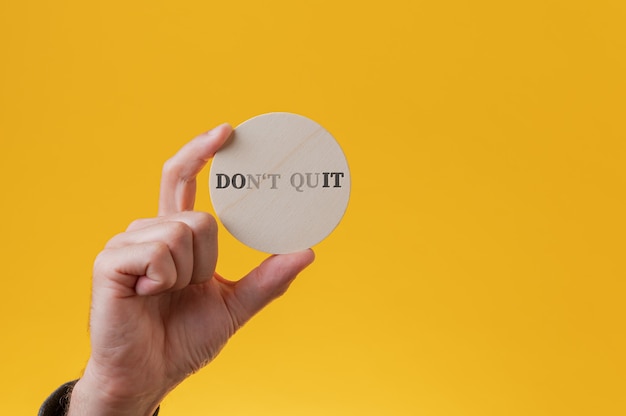 Dont quit sign spelled on wooden cut circle with a few letters vanishing to read a Do it sign.