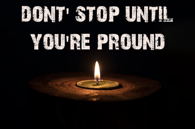 Non fermarti finché non sei orgoglioso - candela bianca con sfondo scuro - in un candeliere di legno.