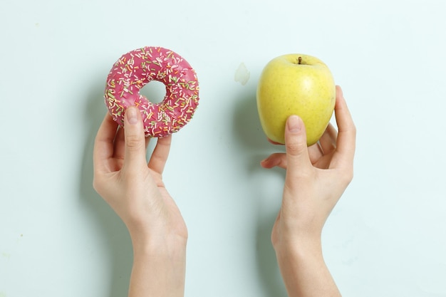 Ciambella e mela in mani femminili. cibo sano e malsano. scelta.