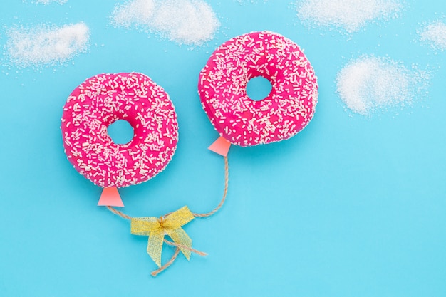 Donut on blue background, donut in a shape of balloon in the sky