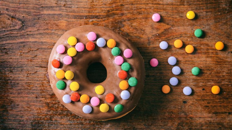 Photo donut chocolate glaze and sprinkles top view and isolated wooden table background