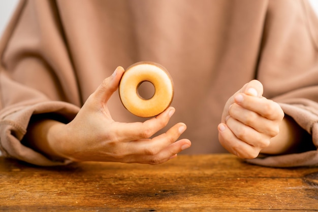 Donut delight Delicate fingers cradle a delicious pastry ring promising a sweet experience