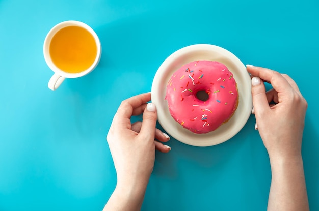Donut en thee op een blauwe achtergrond plat lag
