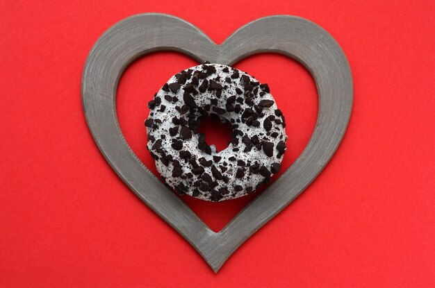 Donut in a frame in the shape of a heart on a red background