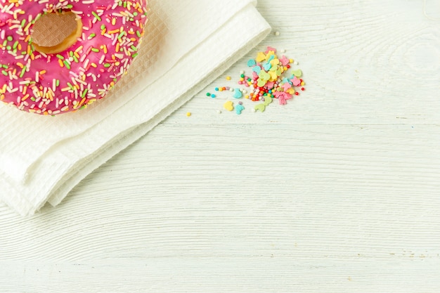 Donut on a kitchen towel and on a wooden table. Photo of sweets with copyspace.