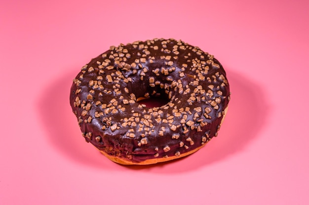 Donut met chocoladeglazuur bovenop geïsoleerd op een roze achtergrond