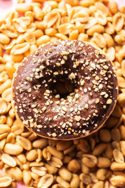 Donut met chocoladeglazuur en pinda's op een roze achtergrond Bovenaanzicht