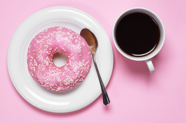 Donut met kop warme koffie, bovenaanzicht. Foto in een roze kleurenschema