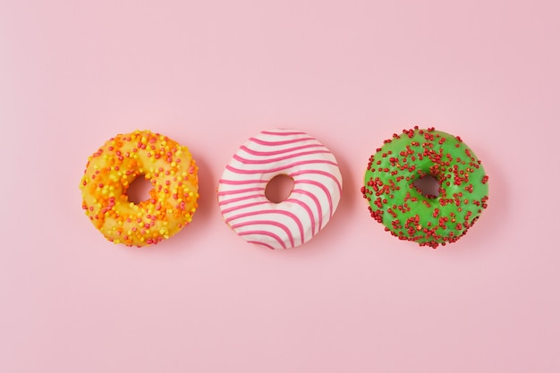 Donut met veelkleurige glazuur op trendy roze achtergrond. Donut zijn traditionele zoete gebakjes. Zoete donuts.