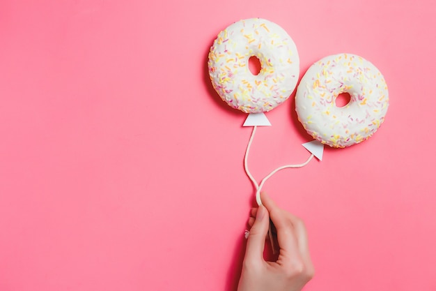 Ciambella su rosa, minimalismo alimentare creativo, ciambella a forma di palloncino in cielo, vista dall'alto con spazio di copia, sfondo tonico