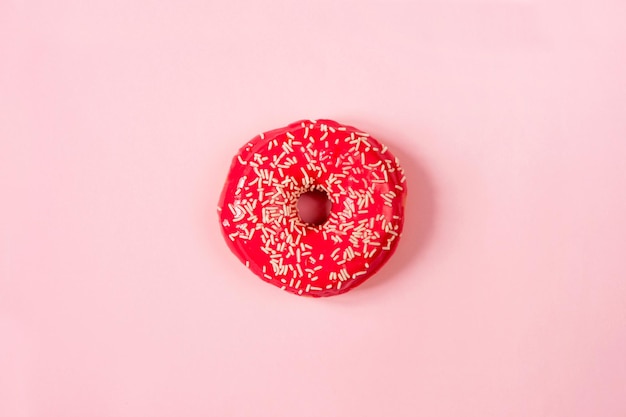 Donut red round with a powder in the center of a pink background top view