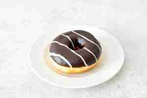 Photo a donut with chocolate frosting and stripes on a plate