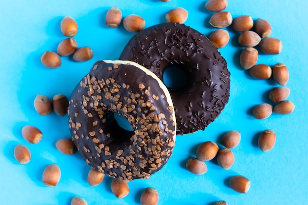 Donut with hazelnuts on a blue background, close up
