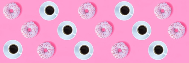 Donut with pink glaze and coffee cup on the pink background Flat lay Pattern Top view