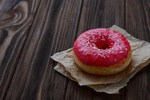 Donut with pink glaze on wooden background