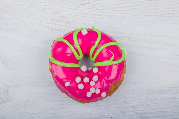 Donut with red glaze on white wooden background