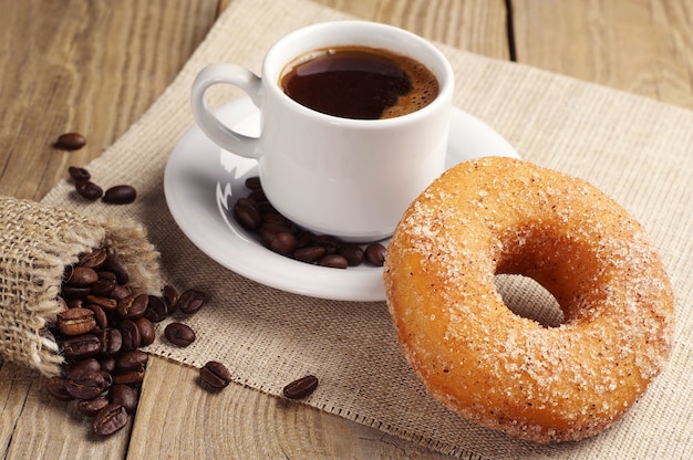 Donut with sugar and cup of hot coffee