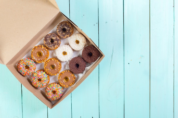 Donuts in box on wooden table. Top view