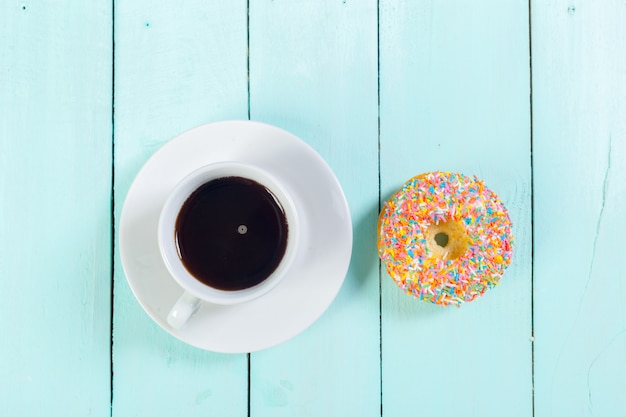 Donuts and coffee on wooden table. Top view