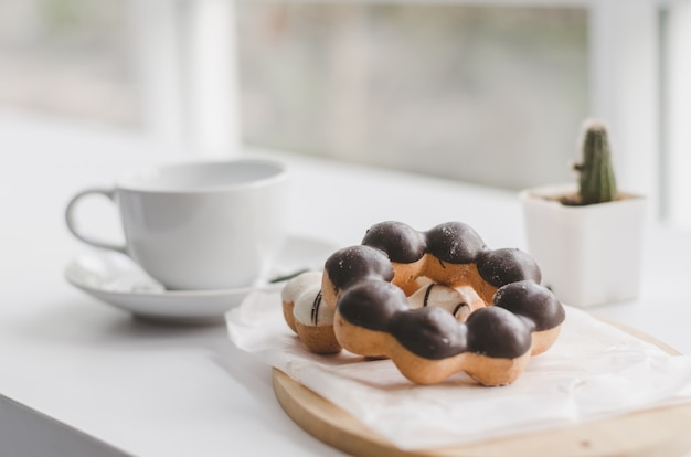 Foto ciambelle e tazza di caffè su una tavola di legno bianca