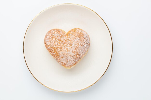 Donuts in de vorm van een hartvormige cruller Zelfgemaakte hartvormige donuts met poedersuiker op witte achtergrond