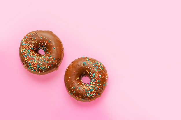 Donuts met chocoladeglazuur en gekleurde hagelslag van ronde vorm op een gekleurde achtergrond