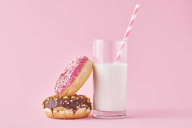 Donuts met glas melk op roze achtergrond