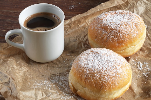 Donuts met poedersuiker en kop warme koffie op verfrommeld papier