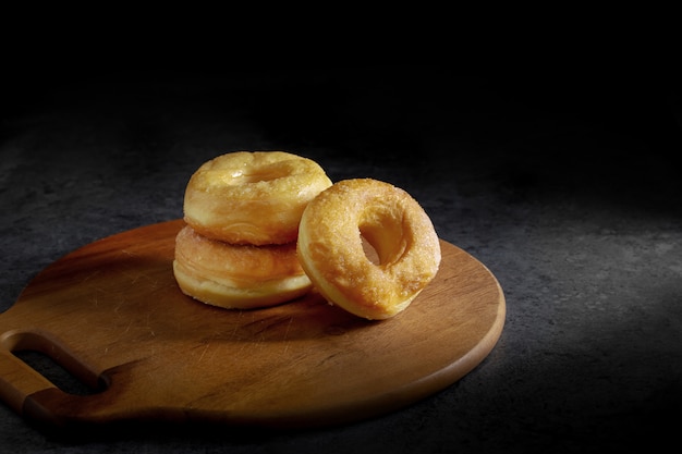 Donuts met suiker op een houten plaat over een donkere lijstachtergrond.
